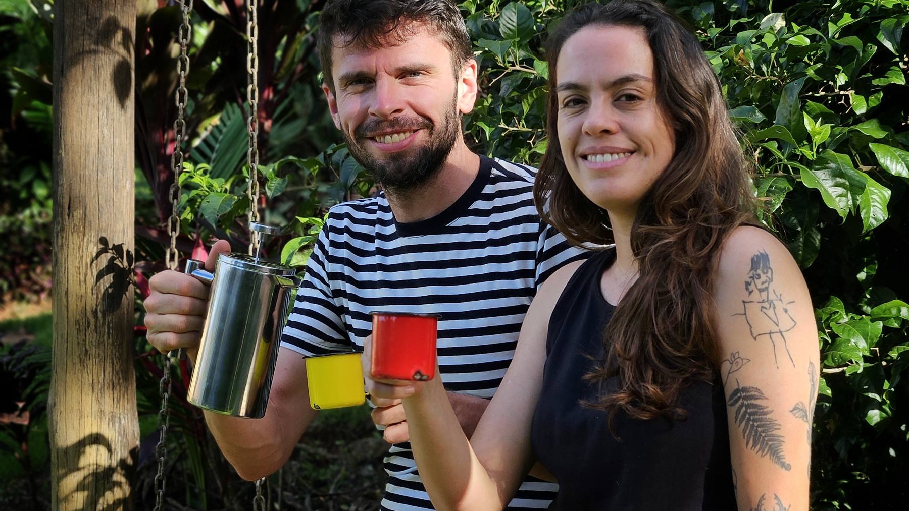 A Maria e o Willem ao lado do balanço no jardim, com a cafeteira e as canecas esmaltadas na mão
