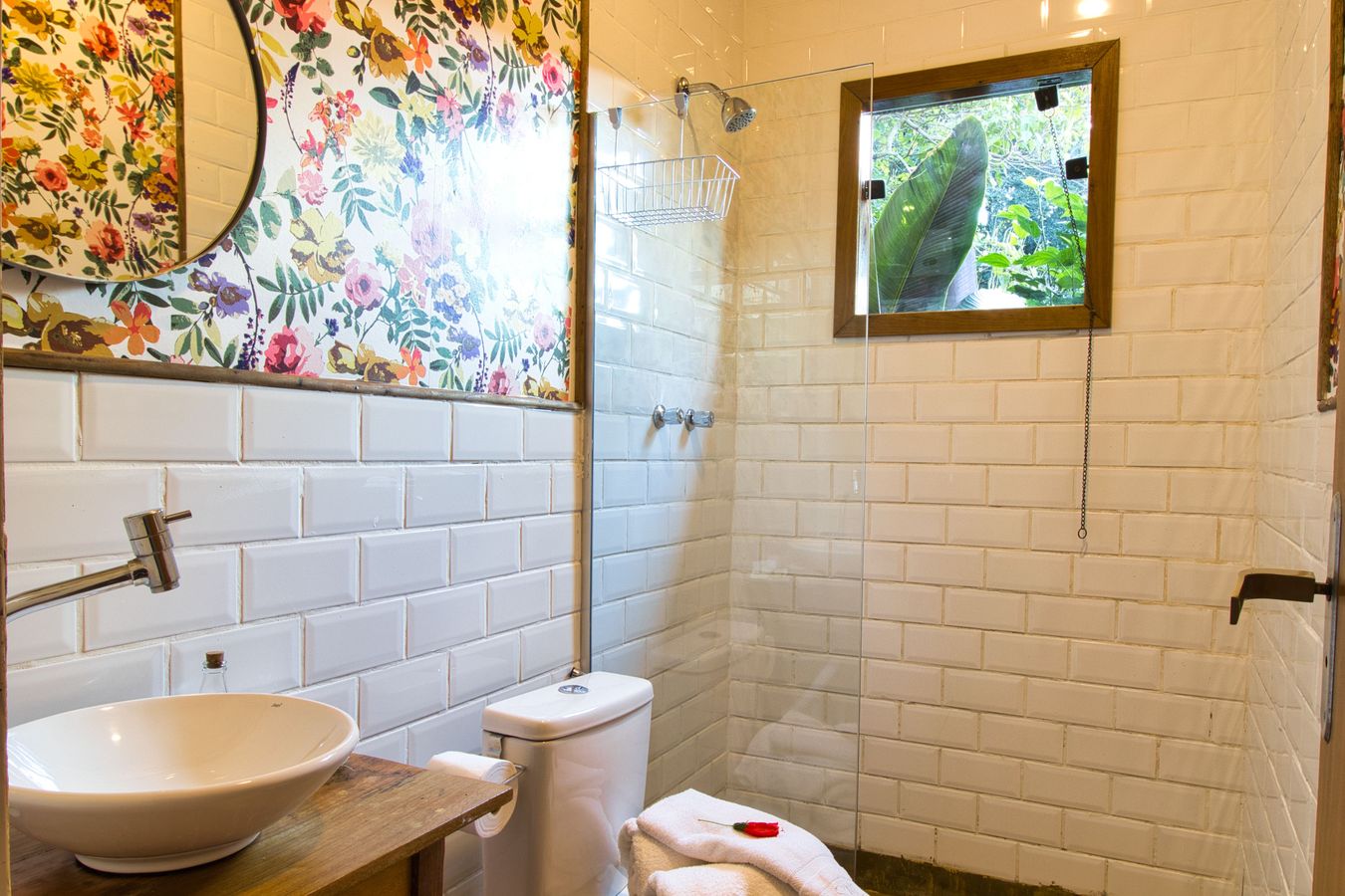 Banheiro da Casinha do Solar, de azulejo branco, com a janelinha para o verde