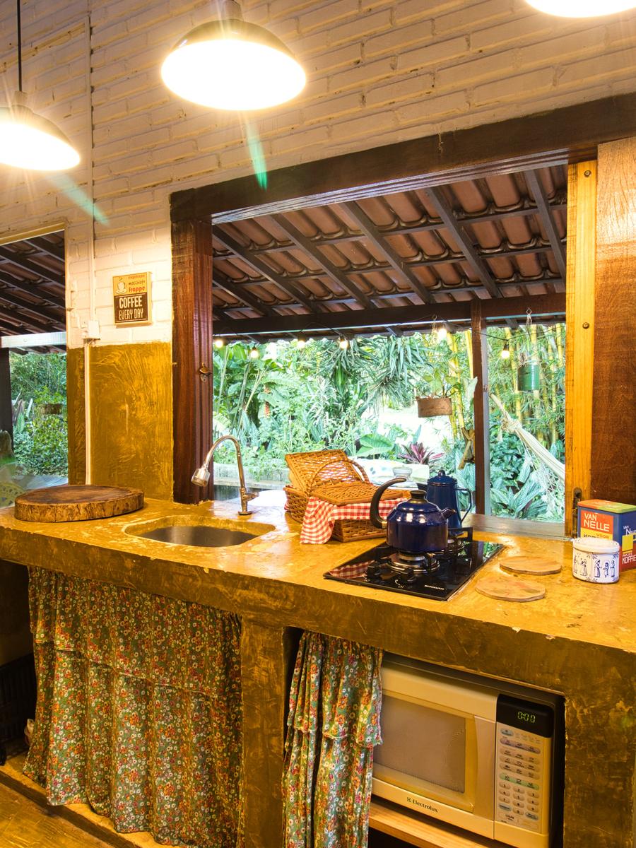 Cozinha da Casinha do Solar, com bancada ocre e janelão aberto para o jardim