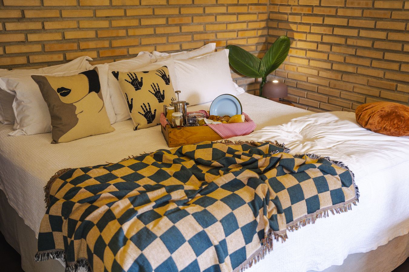 A cama arrumada com a manta xadrez azul e amarela e a bandeja do café