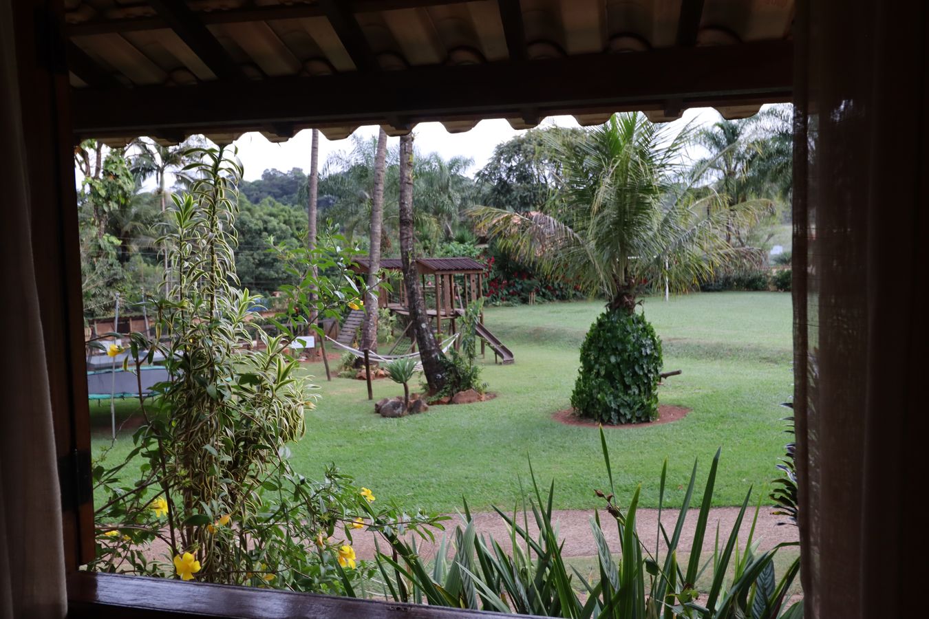O gramado e o parquinho vistos pela janela do chalé