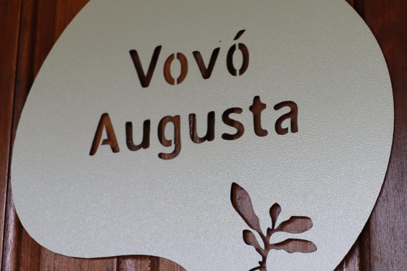 A plaquinha de madeira na porta com o nome da vovó gravado