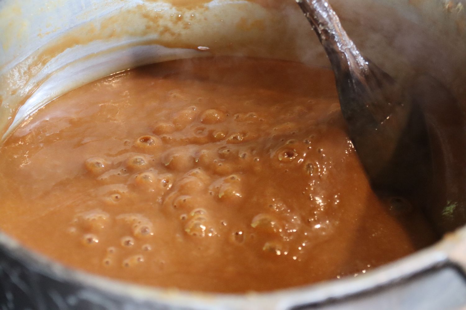 A panela no fogo, mexida com a colher de pau