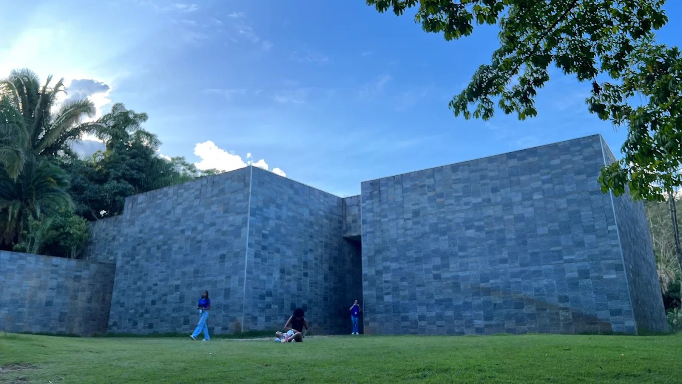 O gramado do Inhotim diante de um dos pavilhões de pedra, com as palmeiras e o céu aberto atrás