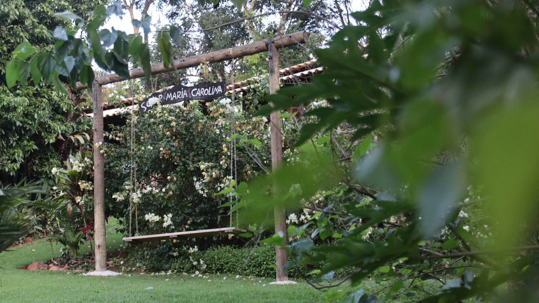 O pergolado de madeira no meio do verde do terreno